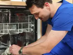 Dishwasher repair technician inspecting and servicing an open dishwasher in Cedar Rapids, IA