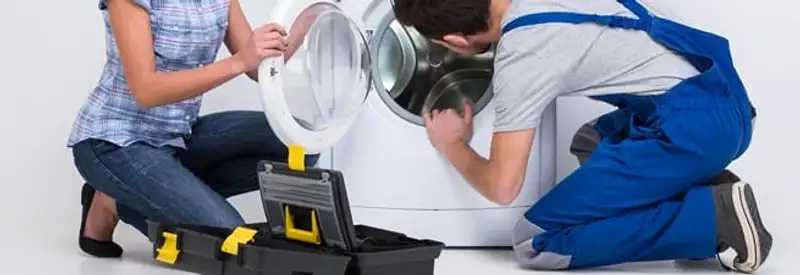 Washer repair technician inspecting a front-load washing machine with tools in Cedar Rapids, IA