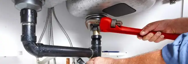 Garbage disposal repair technician tightening the sink drain and disposal connection in Cedar Rapids, IA