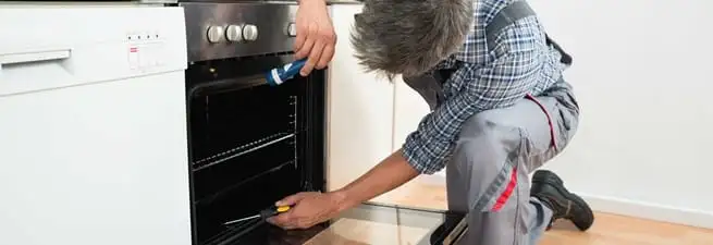 Oven repair technician inspecting and servicing an electric oven in Cedar Rapids, IA