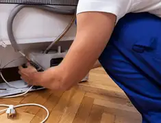 Appliance repair technician fixing refrigerator water line and connections in Cedar Rapids, IA