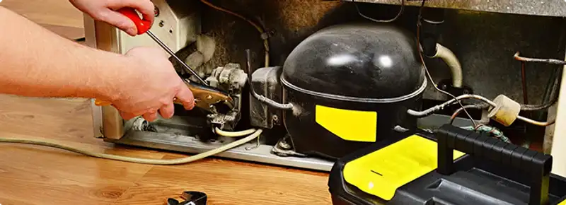 Refrigerator repair technician fixing the compressor and wiring in Cedar Rapids, IA