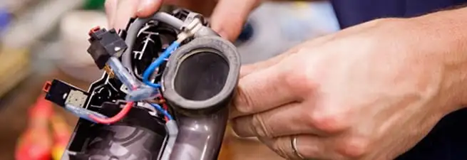 Vacuum repair technician reconnecting wiring and components in Cedar Rapids, IA