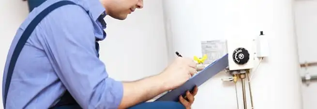 Water heater repair technician inspecting the unit and recording service notes in Cedar Rapids, IA