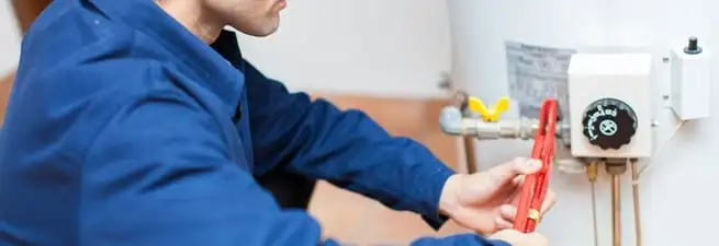Water heater repair technician adjusting the temperature control and gas valve in Cedar Rapids, IA